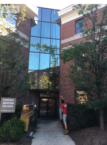 Image of Window Cleaner Using A Water-Fed Pole to Clean 3-Story Building Windows